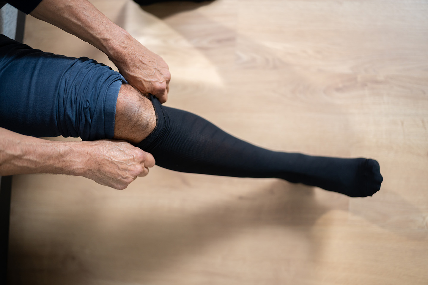 Man Putting On Medical Compression Stockings On Legs